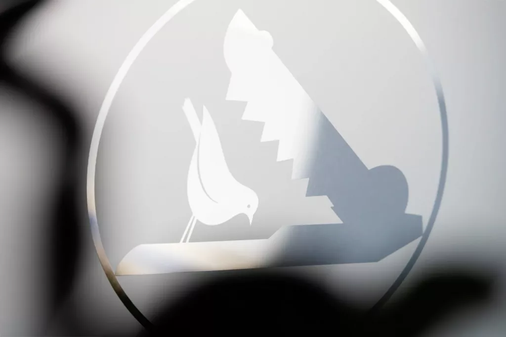 Loepraxis Dr Wilamowskiweb021 Dr Matthias Willamowski Kollegen White dove perched on a jagged stepped triangle inside a circular frosted emblem on glass�