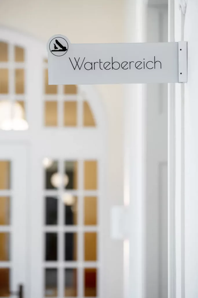 Loepraxis Dr Wilamowskiweb025 Dr Matthias Willamowski Kollegen Sign reading Wartebereich Waiting area on a white wall inside a bright room