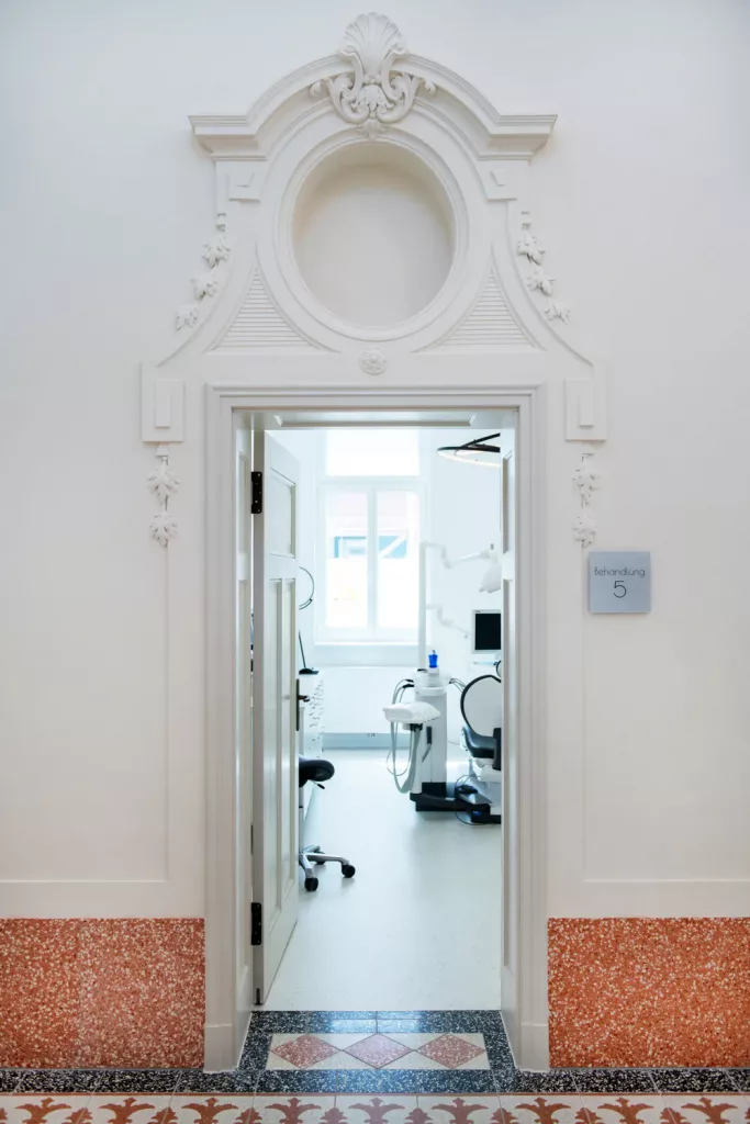 Loepraxis Dr Wilamowskiweb036 Dr Matthias Willamowski Kollegen Ornate white doorway opening to a bright dental treatment room with a chair and equipment visible