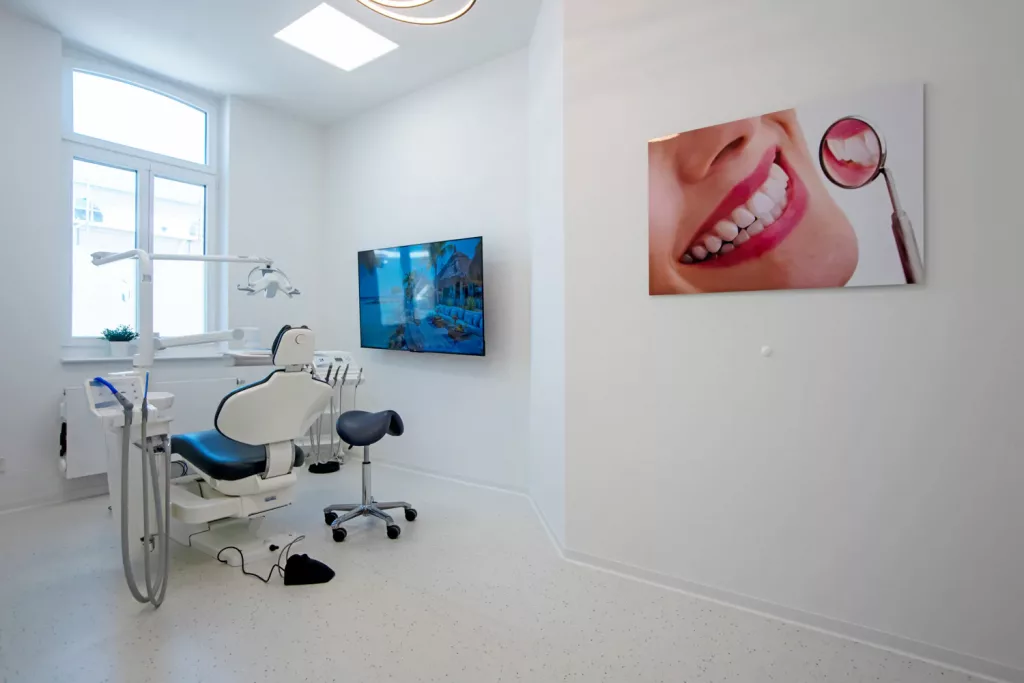Loepraxis Dr Wilamowskiweb037 Dr Matthias Willamowski Kollegen Modern dental clinic treatment room with white chair equipment and a wall mounted TV large window to the left